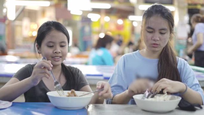 两姐妹亚洲女孩和十几岁的女孩在市场食堂吃饭前脱下口罩