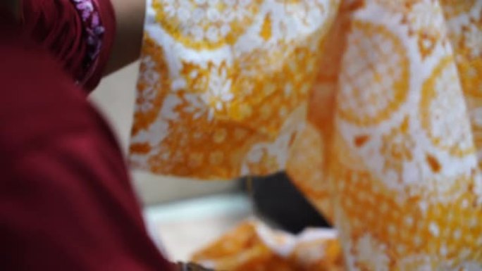 2020年12月22日印度尼西亚独奏: 在苏拉卡尔塔制作蜡染薄纱的传统倾斜，背景是彩色织物