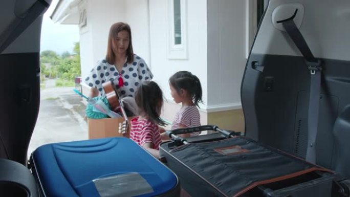 亚洲女童帮助父母携带手提箱和纸板箱，里面装有东西，在慢动作拍摄的移动日搬迁。