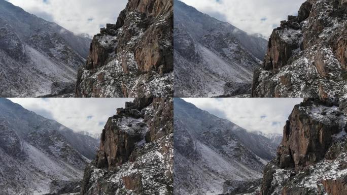 鸟瞰图相机的近距离跨度，在早春的山坡上，高高的岩壁旁，绿草如茵，雪如山