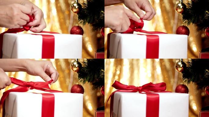 带有圣诞灯背景的礼品盒上的手系丝带。