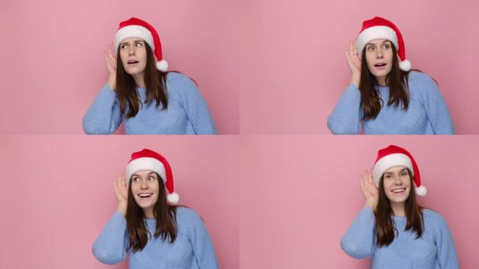 穿着圣诞红色帽子的可爱年轻女子试着听到你偷听，专心听着，穿着舒适的蓝色毛衣，孤立在粉红色背景工作室。