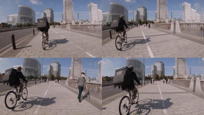 带着黑色背包的年轻人快递员在街上骑着自行车穿过城市，运送食物。视频是从后面拍摄的。送餐概念。