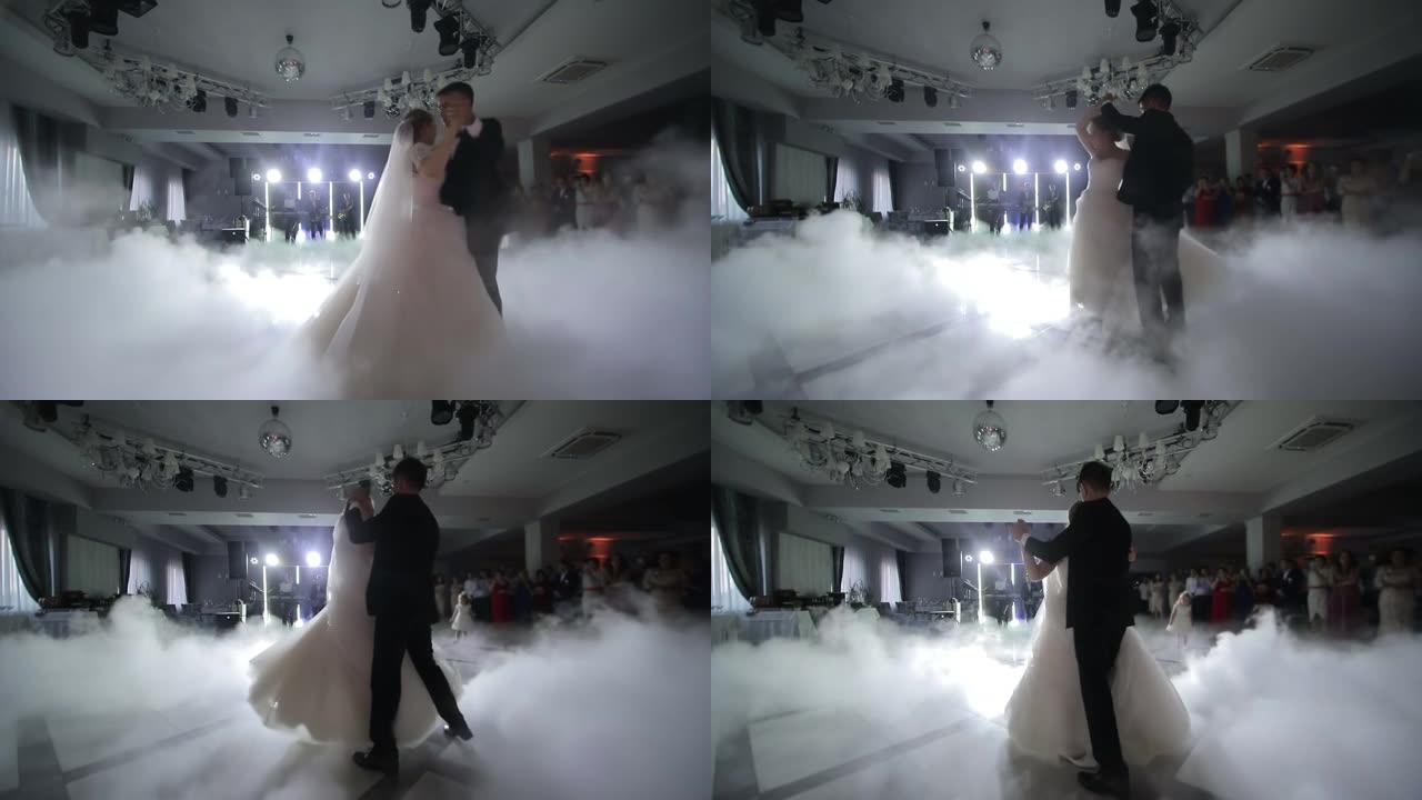 婚礼上新娘的舞蹈。用白光突出显示的浓烟。新婚夫妇在婚礼上的第一支舞