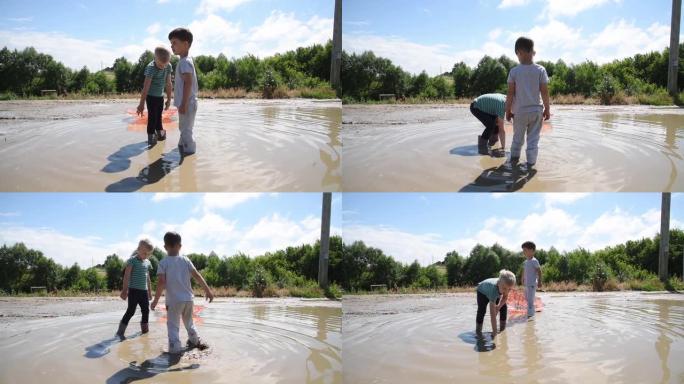 晴天，两个男孩在乡村道路上的大水坑里玩耍