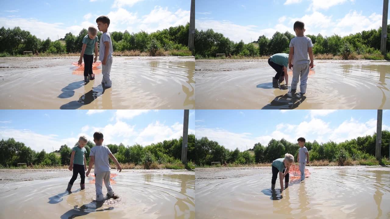 晴天，两个男孩在乡村道路上的大水坑里玩耍