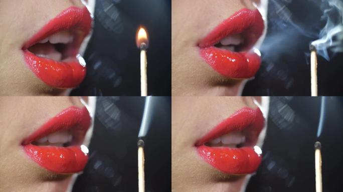 细节特写微距拍摄了一个女孩的嘴唇，上面涂着闪亮的红色唇膏，吹出了黑色工作室背景上燃烧的火柴的火焰。4
