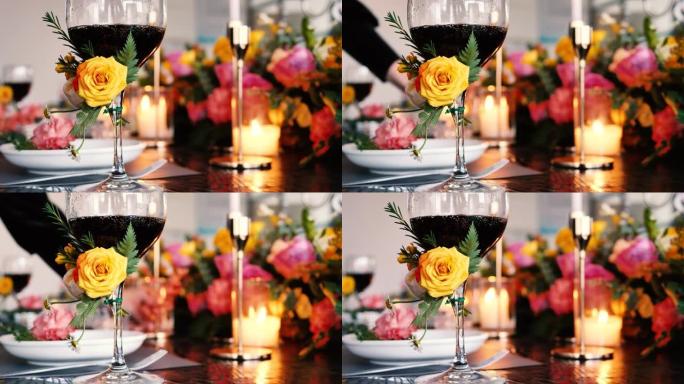 餐桌上装饰着美丽的花朵，酒杯和蜡烛灯，带有女服务员准备装饰品的模糊背景，4k慢动作镜头，b卷镜头。