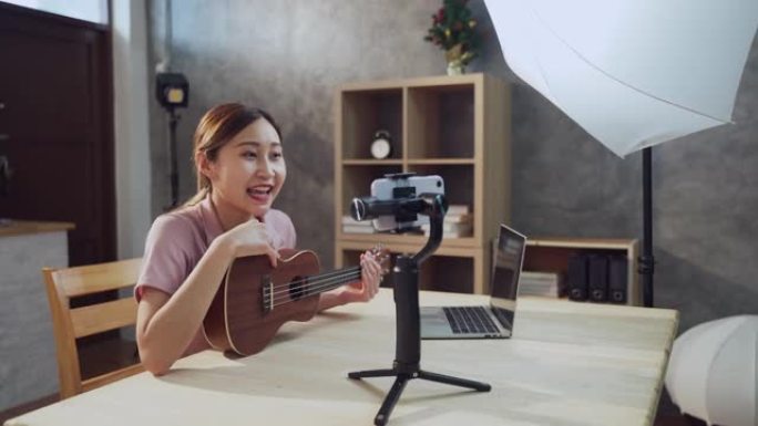 年轻的亚洲企业家少女在智能手机前教吉他