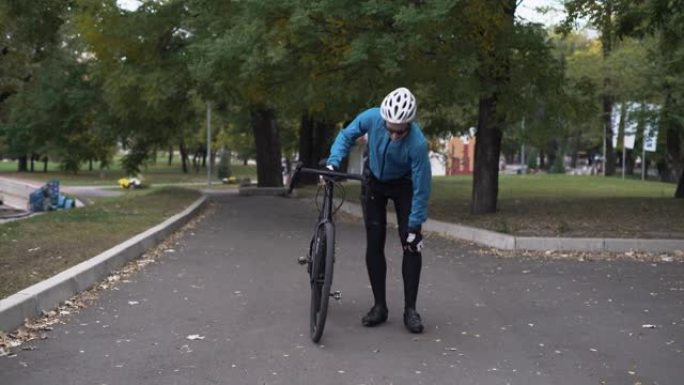 男骑自行车的人一瘸一拐地穿过公园。膝盖疼痛。