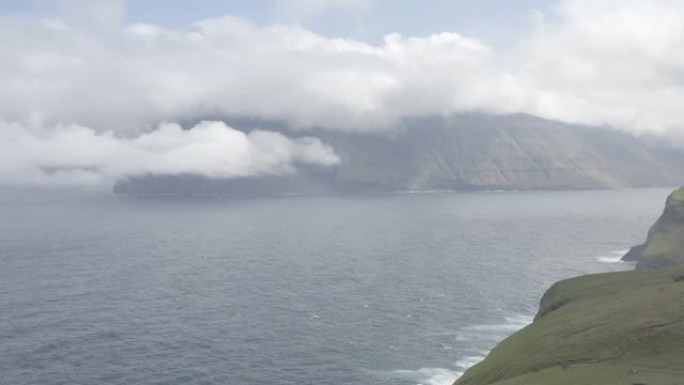 无人机飞越位于丹麦法罗群岛上的卡尔索伊岛 (Kalsoy Island) 上绿色崎cliff的悬崖山
