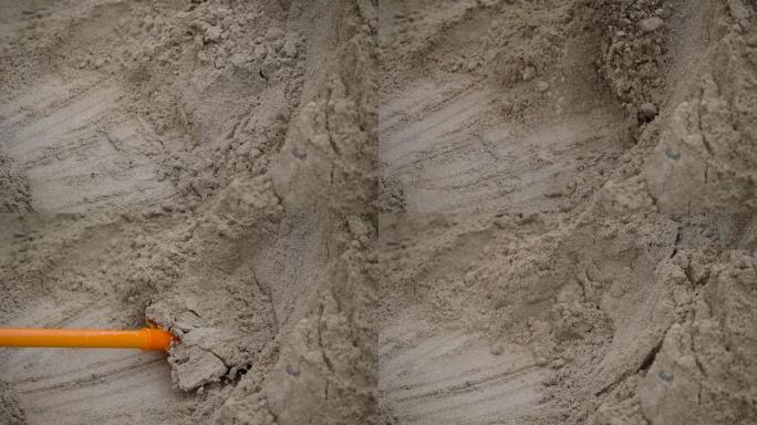 一名男子用轻塑料铲收集沙子用于建筑工作
