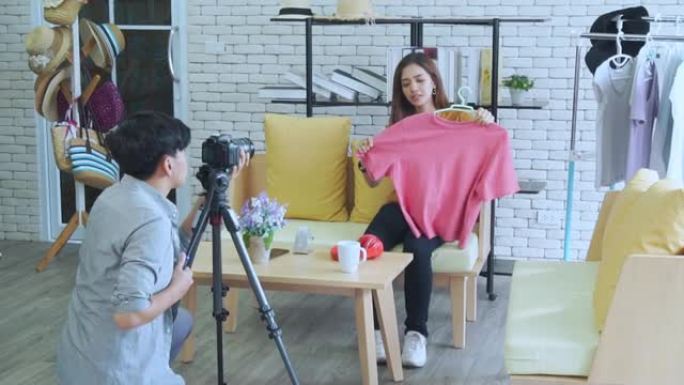 年轻的亚洲夫妇博主录制vlog视频，有影响力的人在工作室的社交媒体上在线展示和销售服装，在线学习教程