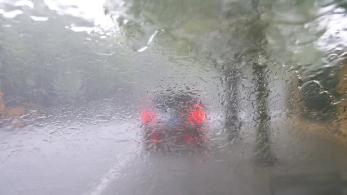 通过带有大雨的车窗观看道路交通，在雨中从汽车挡风玻璃观看交通，4k b滚动镜头，重点是降雨。