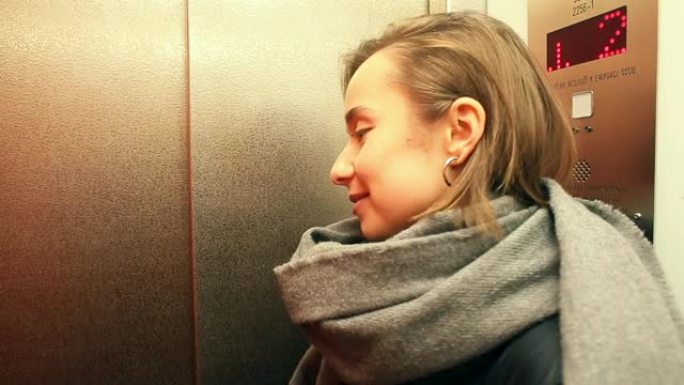 女人围巾坐电梯，等待出口。自动运送乘客水平。