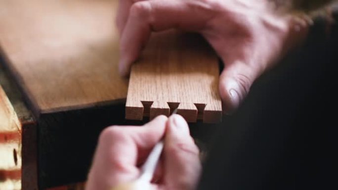 细木工用木凿将燕尾榫缝雕刻成橡木木板。木工、工艺、手工艺品。木工工具的声音