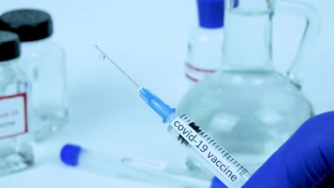冠状病毒感染疫苗的演示，新型冠状病毒肺炎大流行的治疗方法，在医生手中，带有液体的注射器，特写