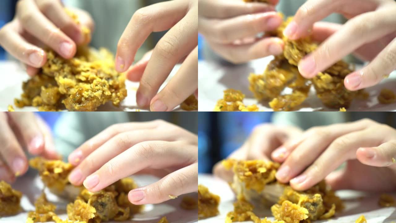 一个小孩在快餐店吃炸鸡。鸡肉几乎吃光了。用手剥掉鸡皮。