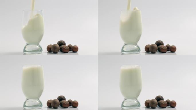 将新鲜牛奶倒入白色背景的透明玻璃杯中。健康食品和乳制品概念。慢动作飞溅与新鲜白色营养饮料的滴特写，特