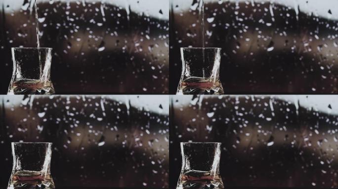将威士忌倒入玻璃杯特写。在窗外雨水的背景下倒威士忌
