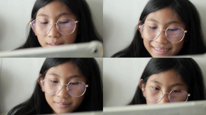 亚洲女孩戴着眼镜，在家沙发上使用数字平板电脑，生活方式理念。