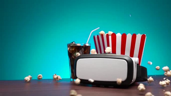 慢动作爆米花从盒子里飞出。桌上摆着一个虚拟现实耳机、一盒爆米花和一杯加冰的可乐饮料。
