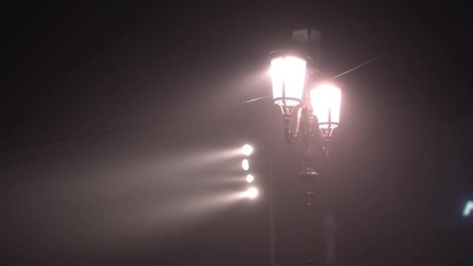 雾蒙蒙的黑暗中带有电缆发光的老式路灯