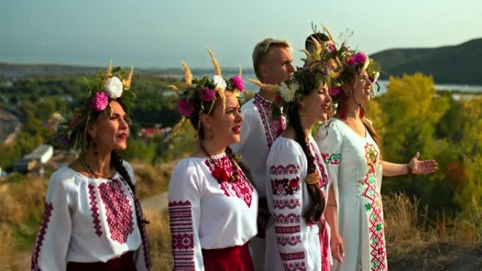 穿着民间服装，头上戴着花圈的美丽年轻妇女在大自然中唱歌，这是一个民间节日。穿着带有刺绣装饰品的民间服