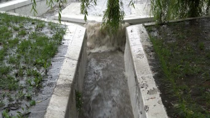 特写，大雨期间，一股快速的脏水通过雨水下水道的石沟流入河中。天气不好。概念。4K。