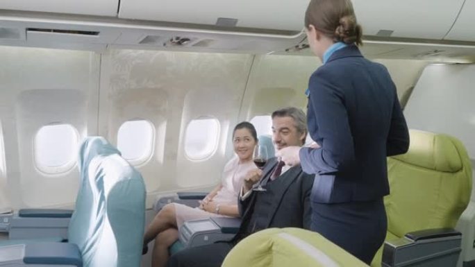 空姐在飞机上的航空公司工作人员在飞机上向商务舱的商人提供红酒。