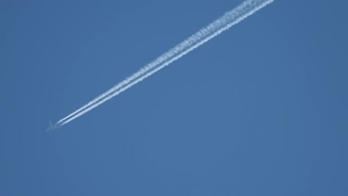 喷气式客机在高空飞行，在湛蓝的天空中留下凝结尾迹