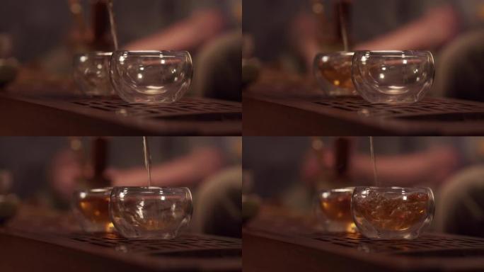 中国省份茶室的舒适氛围。瓷茶壶里的一股香茶充满了两个玻璃碗。特写，暖光。慢速