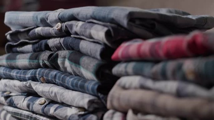 侧视图: 女人的手将男式衬衫放在整齐的堆中