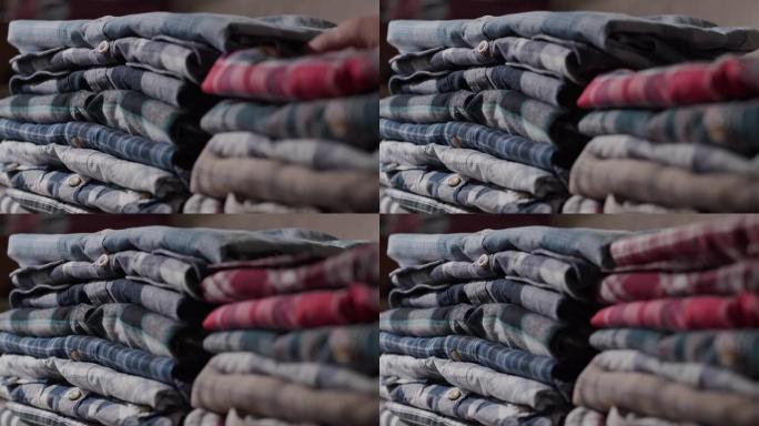 侧视图: 女人的手将男式衬衫放在整齐的堆中