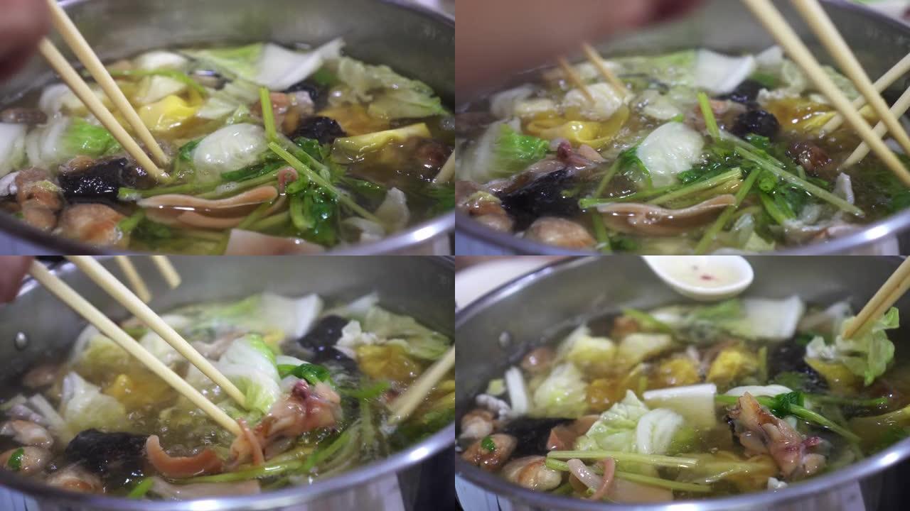 特写中式清汤火锅海鲜蔬菜用筷子和手吃