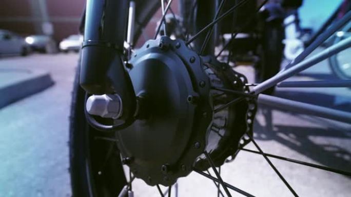 从锐利到模糊车轮和电机的电动自行车视图从下面显示。电动自行车电机摄像机运动滑动特写。停车场有自然照明