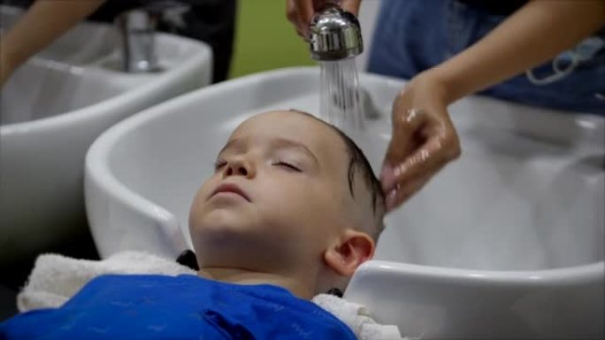 Parekhmacher，给学龄前儿童理发后，洗头，用洗发水肥皂，孩子休息，并在剪发后享受洗头的乐趣