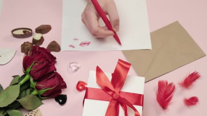 女人的手用笔在纸上写一封情书。粉色背景。