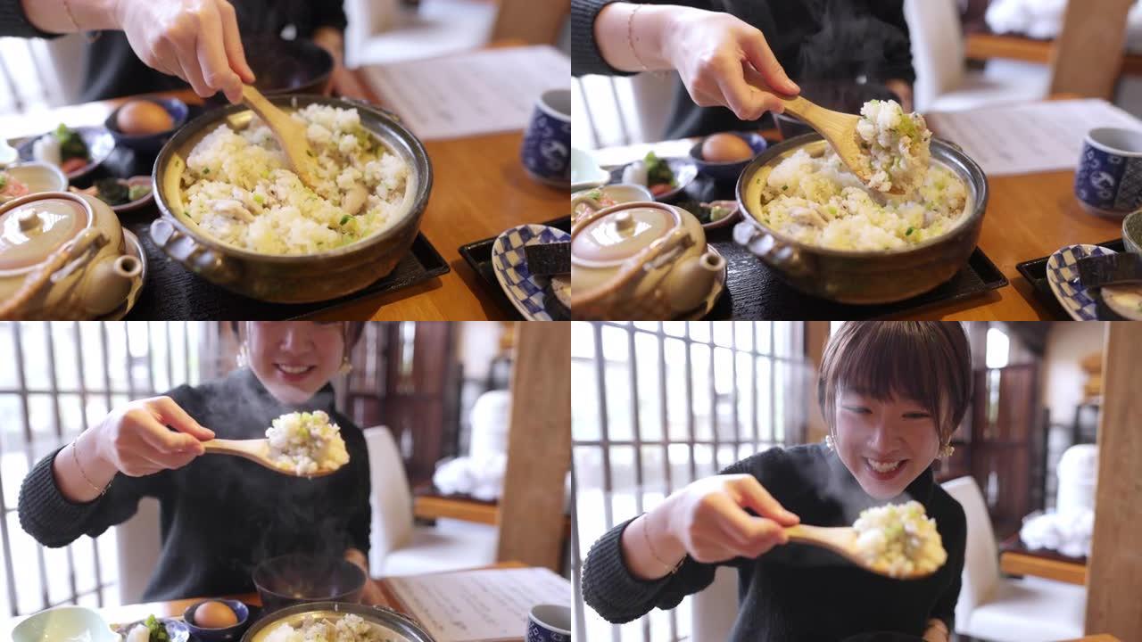 年轻女子在日本餐厅将米饭 (donabe gohan) 端到碗中