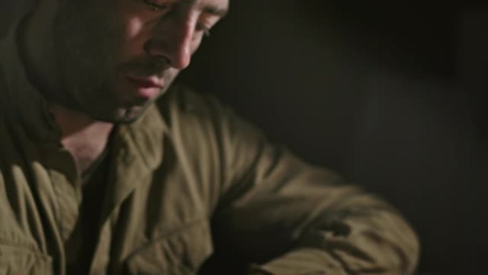 一名士兵坐在黑暗的房间里，在煤油灯的灯光下计算着行动计划，思考着军事任务。近距离