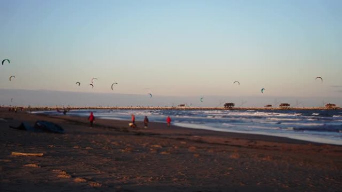 运动员做风筝冲浪时，人们沿着海滩散步