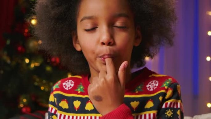 可爱的卷发非洲裔美国女孩喜欢尝试糖衣来装饰饼干。新年快乐假期和温暖家庭之夜的概念。特写。慢动作