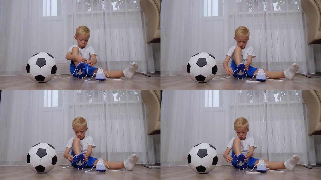 一个小男孩坐在地板上，学习将鞋带系在足球靴上。