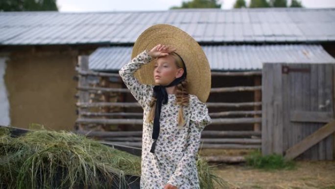 美丽的女孩，戴着两个帽子辫子，穿着浪漫的衣服，看着乡村风景。穿着帽子和衣服的乡村女孩在后院的海瑞克背