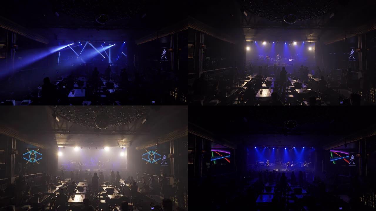 一位歌手与音乐乐队一起在disco pub club酒吧的舞台音乐会上表演，并带有照明激光束聚光灯表