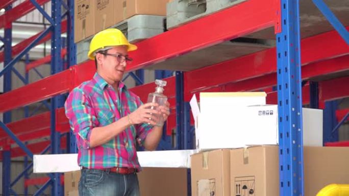 仓库高级亚洲工人检查已交付的纸板箱，邮政工人将包裹发送到配送仓库的玻璃瓶。一名服务人员，在空的储藏室