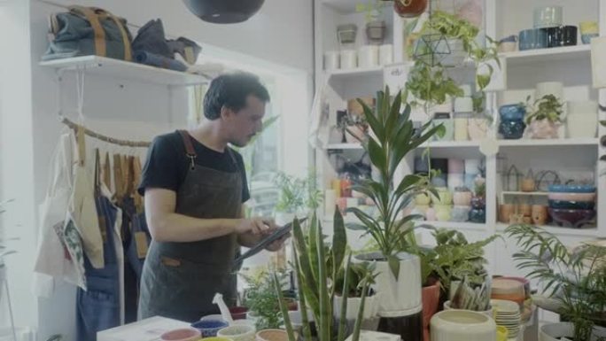 成年工人在他的植物学精品店的数字平板电脑上订购产品