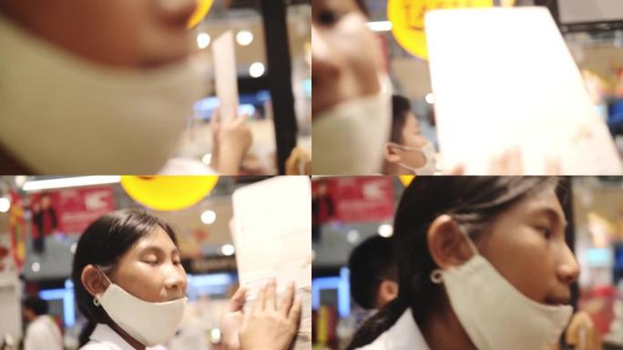 亚洲学童戴着口罩在美食广场等待食物，这是新的正常概念。
