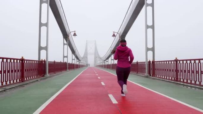 年轻胖乎乎的高加索女孩在桥上奔跑。背部拍摄慢动作。紫色套装