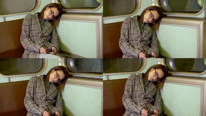 一名年轻女子在地铁列车上睡着了。耳朵里戴着耳机的女孩。旧地铁车